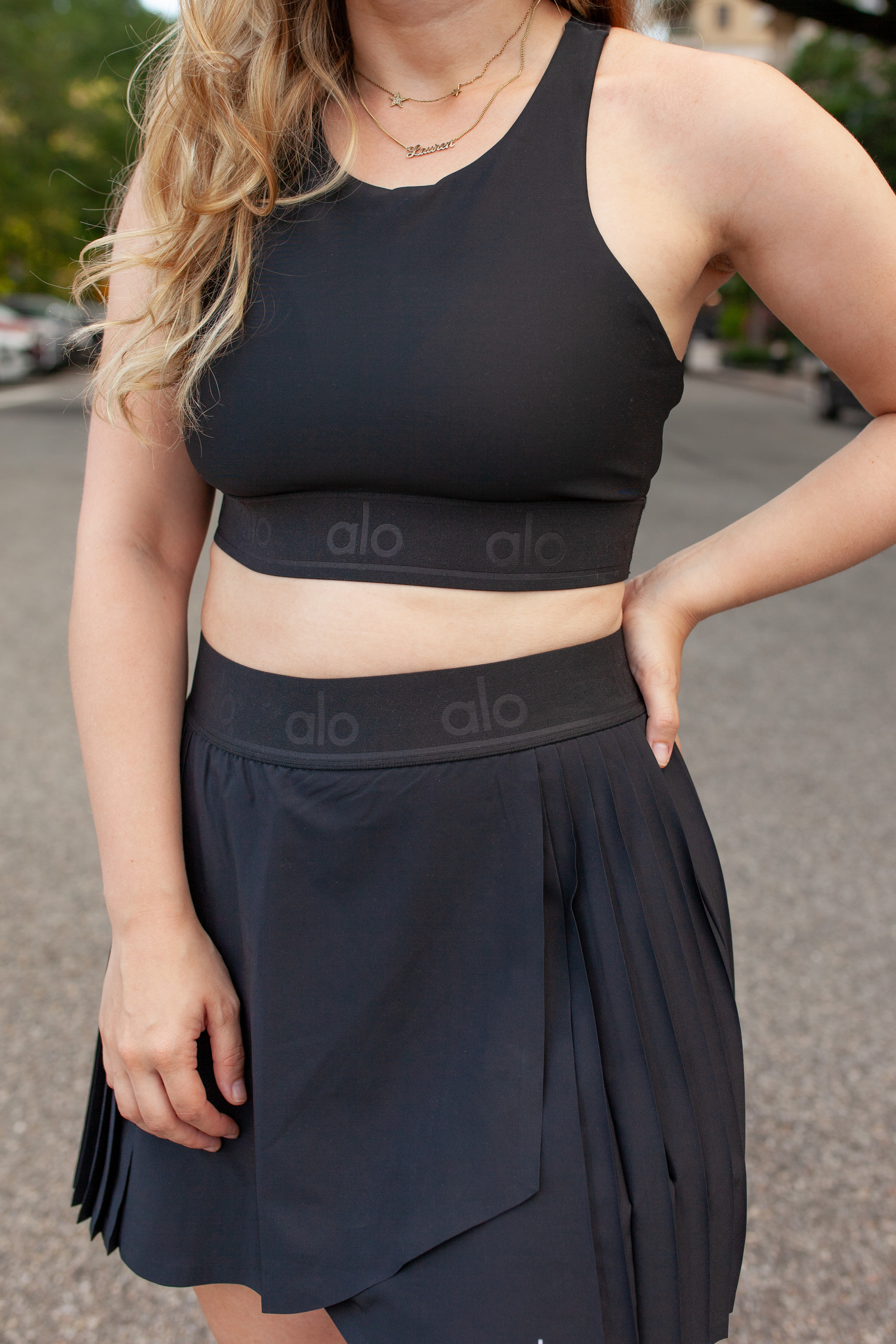 girl wearing black tennis skirt and sports bra from alo yoga